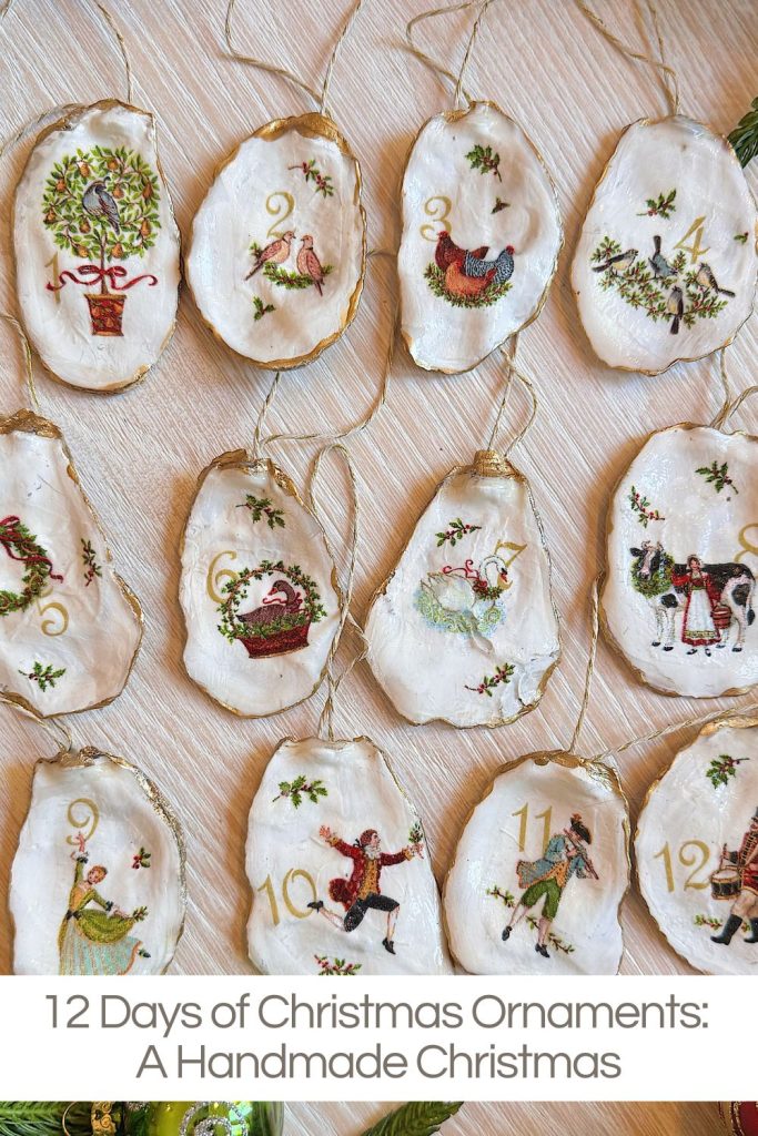 Twelve handmade Christmas ornaments painted on oyster shells, each depicting a scene from the 12 Days of Christmas, arranged on a light wood surface.