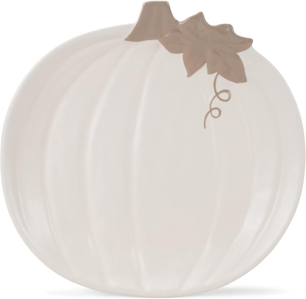 A ceramic plate shaped like a pumpkin, featuring a beige pumpkin body and a stem with a leaf detail at the top.