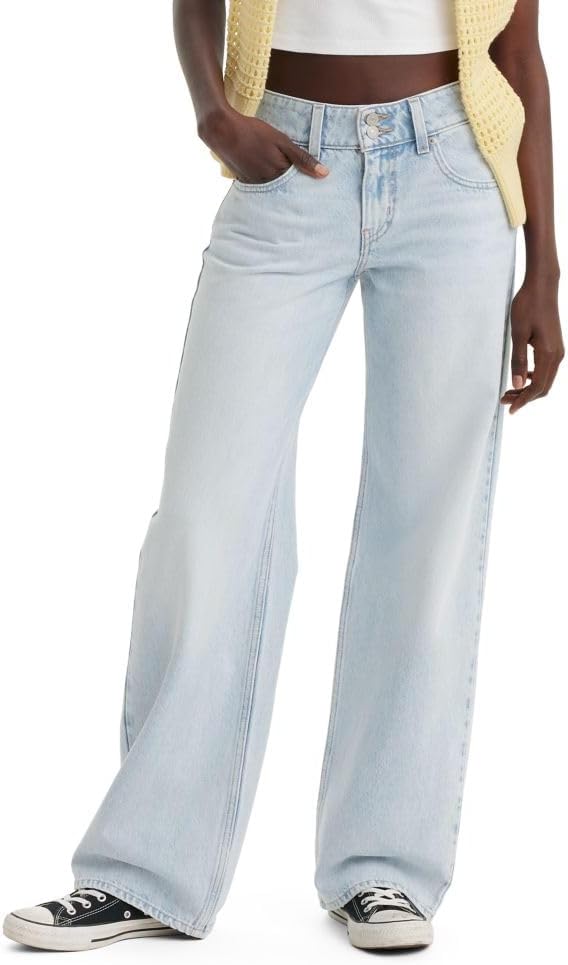 A person wearing light wash wide-leg jeans, a white top, a yellow knit vest, and black-and-white sneakers with one hand in their pocket—ready to shop the latest styles during Amazon Prime Big Deal Days.