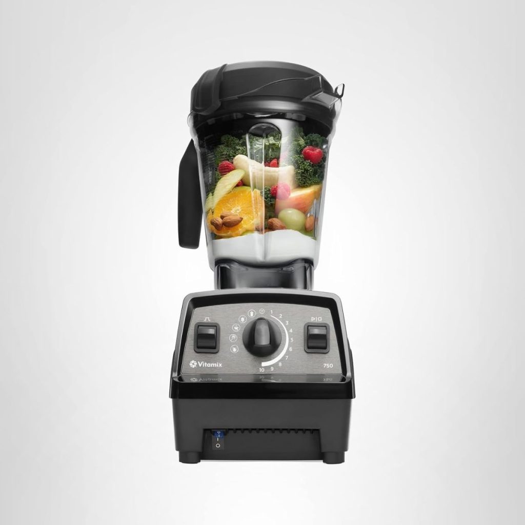 A black countertop blender filled with assorted fruits and vegetables, including oranges, bananas, and leafy greens, stands against a plain light background—perfect for healthy smoothies during Amazon Prime Big Deal Days.