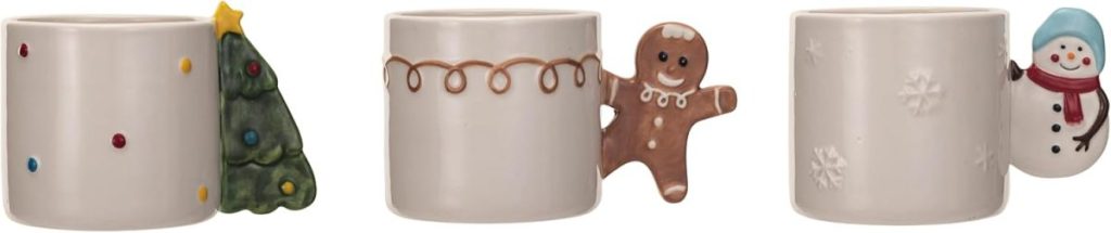 Three white ceramic mugs with festive handles: one with a Christmas tree, one with a gingerbread man, and one with a snowman.
