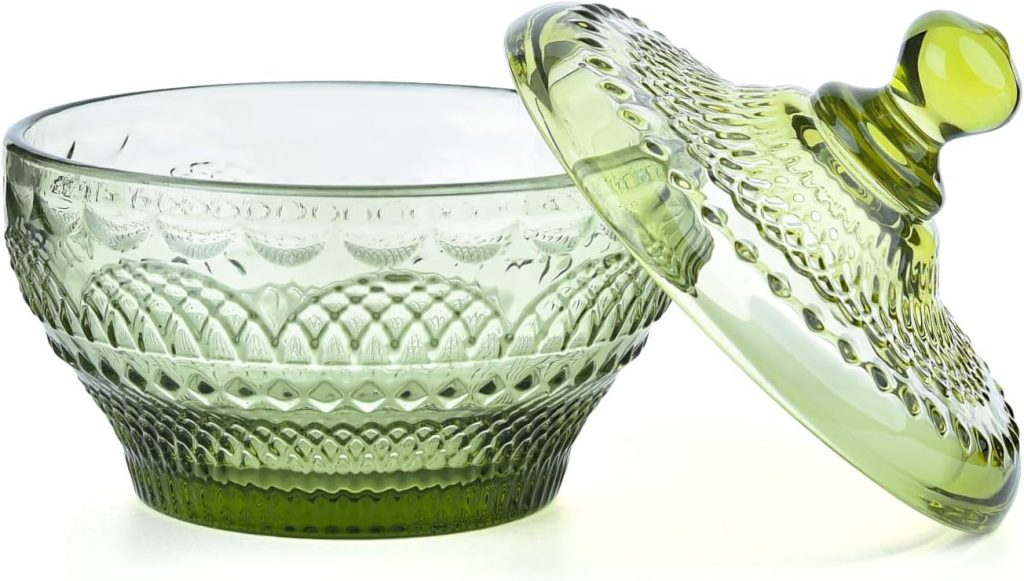 A green glass bowl with a matching patterned lid, shown slightly tilted off the bowl.