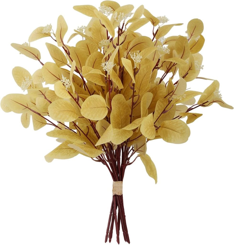 A bundle of artificial yellow leaves with small white flowers, tied together at the stems with string.