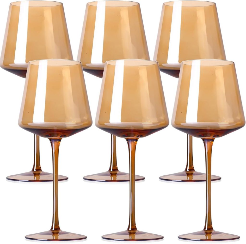 Six amber-tinted wine glasses with long stems are arranged in two rows against a white background.
