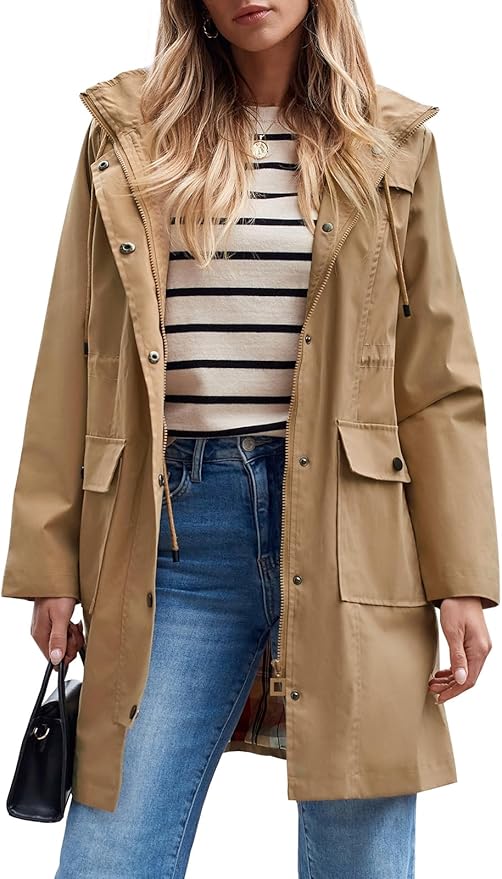 Woman in Portugal wearing a tan hooded raincoat over a striped shirt and blue jeans, holding a black handbag, photographed from mid-thigh up.