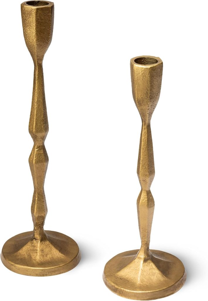 Two gold-colored Porto metal candlesticks with geometric, textured designs and varying heights, placed on a white background.