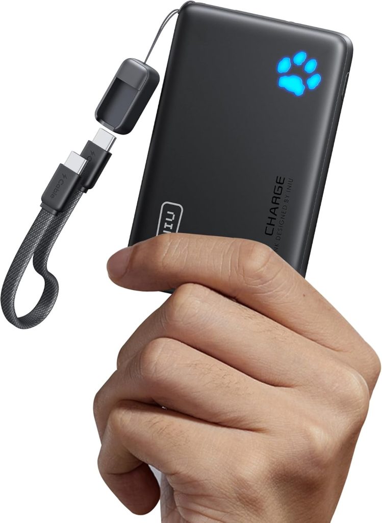 A hand holding a black portable power bank with a glowing blue paw print icon and a short charging cable attached, perfect for Amazon Prime Big Deal Days.