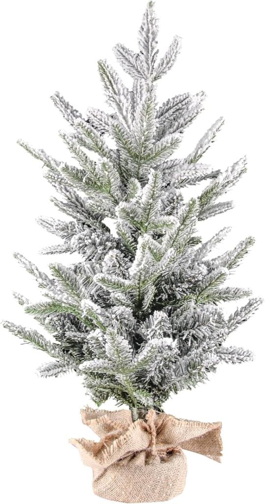 Artificial pine tree with snow-frosted branches, wrapped at the base in burlap fabric.