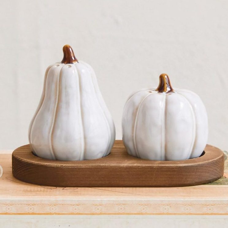 Two ceramic pumpkin-shaped containers sit on a wooden tray, placed atop a stack of vintage books—an inspiring touch for those seeking charming pantry cabinet ideas.