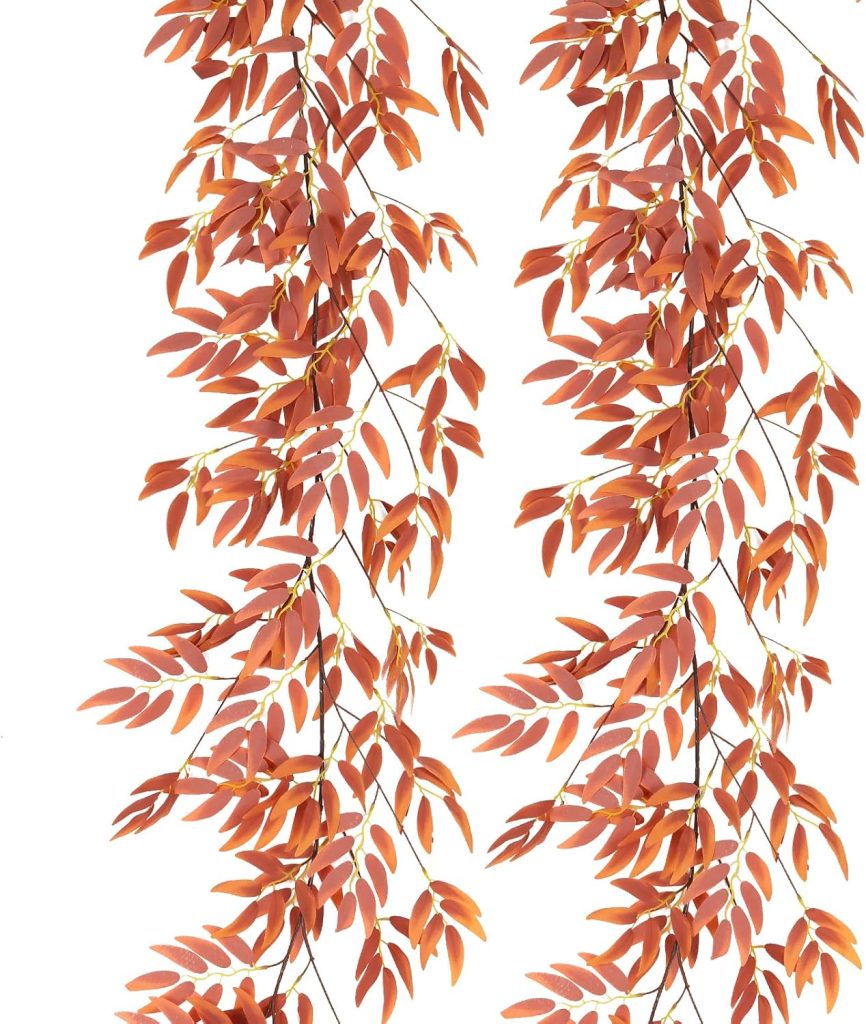 Two cascading branches with numerous small, reddish-orange leaves are pictured against a white background, reminiscent of autumn scenes with painted pumpkins.