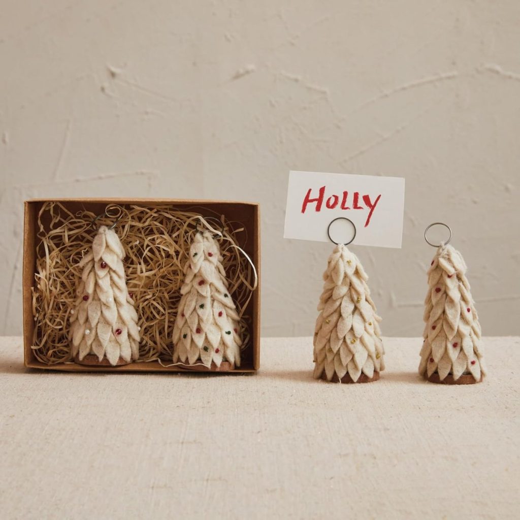 Three felt Christmas tree ornaments in a box with straw, and two similar ornaments made with Air Dry Clay stand outside—one holding a place card labeled "Holly.