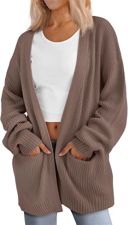 Woman wearing a loose, taupe-colored knit cardigan over a white crop top and light blue jeans, with hands in the cardigan pockets—perfect for cozying up during Amazon Prime Big Deal Days.