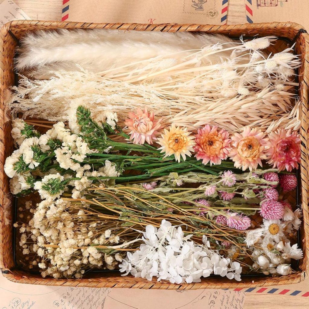 A wicker basket filled with assorted dried flowers and grasses in various colors, including white, cream, pink, and yellow, neatly arranged in sections.