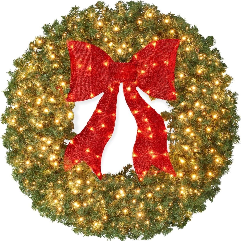 A green Christmas wreath decorated with warm white lights and a large red bow—perfect for adding festive cheer to your home this Amazon Prime Big Deal Days.