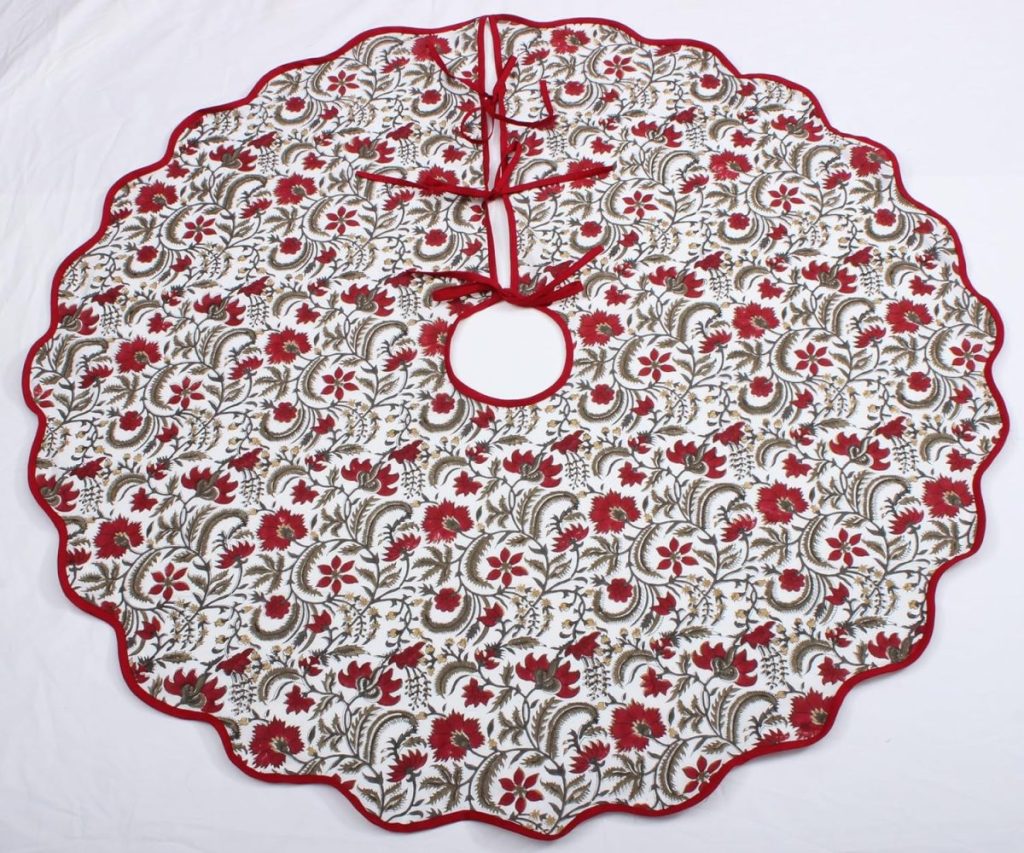 A circular Christmas tree skirt featuring a red, green, and gold floral pattern with red trim and tie closures, displayed on a white background—perfect for decking your halls during Amazon Prime Big Deal Days.