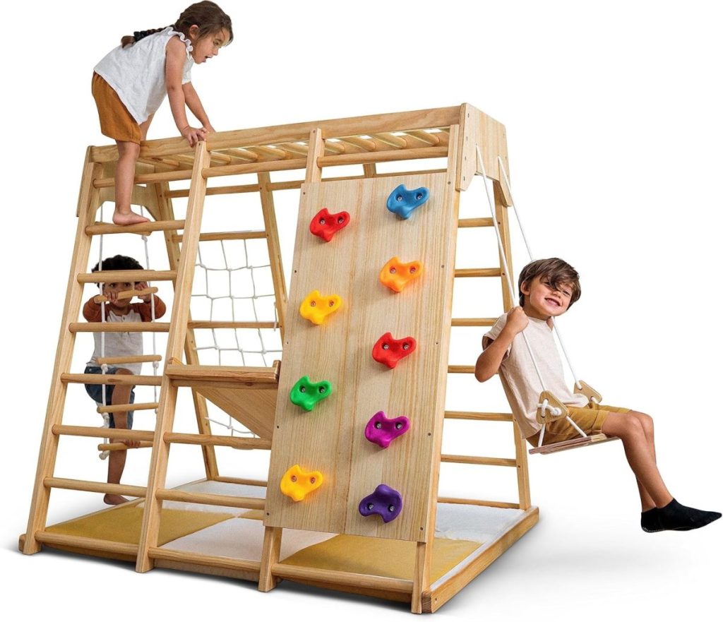 Three children play on a wooden indoor climbing structure with a ladder, climbing holds, rope net, and a swing—perfect for fun at home and great to find during Amazon Prime Big Deal Days.