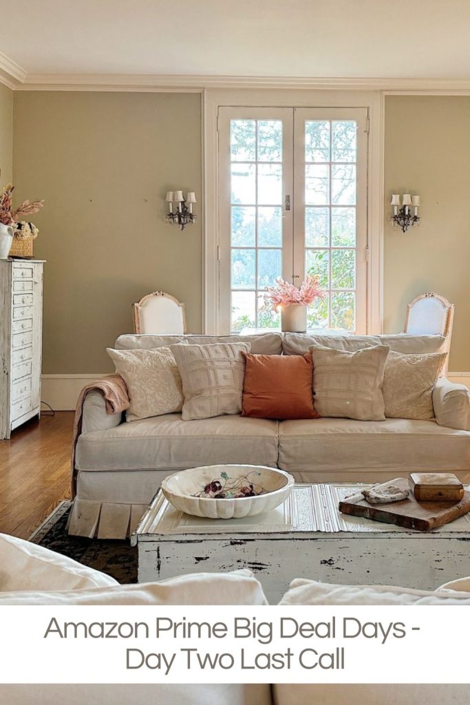 A neutral-toned living room with a white sofa, decorative pillows, a wooden coffee table, and large French doors letting in natural light. Text overlay reads: "Amazon Prime Big Deal Days - Day Two Last Call.