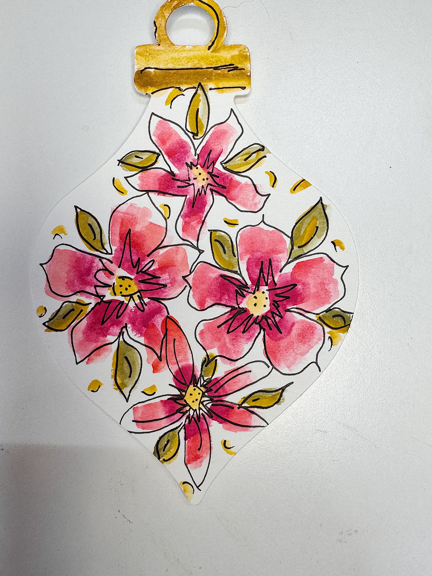 A hand-drawn ornament featuring pink flowers with green leaves and yellow accents, outlined in black on a white background.