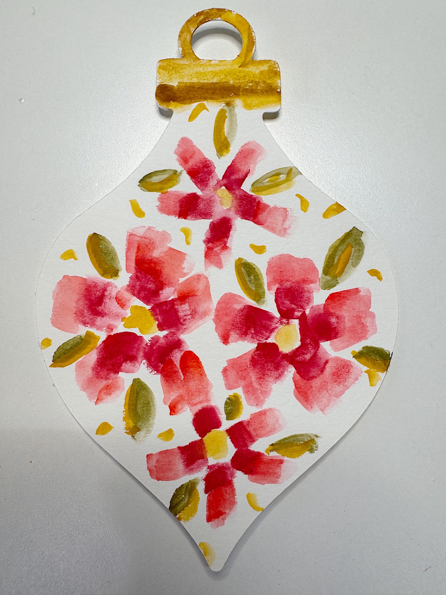 A hand-painted ornament-shaped card featuring red and pink flowers with green leaves and yellow accents on a white background.