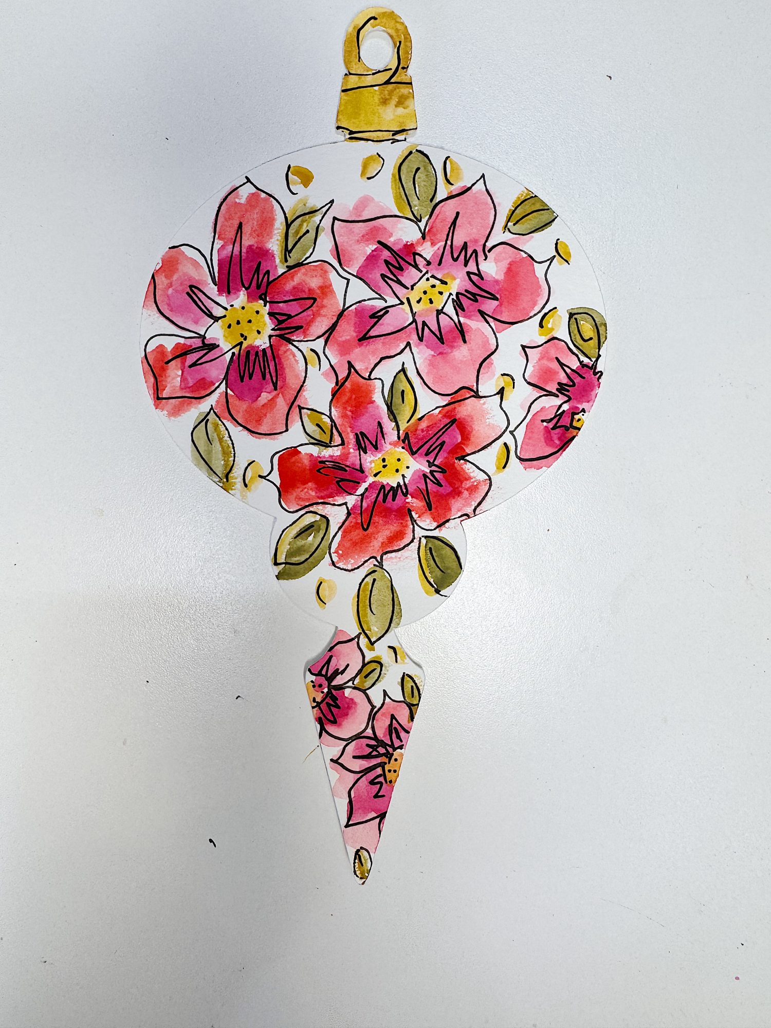 A hand-painted ornament with a gold top, decorated with red and pink flowers and green leaves on a white background.
