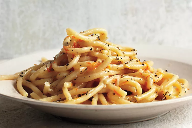 A plate of spaghetti tossed with a creamy sauce and sprinkled with cracked black pepper.