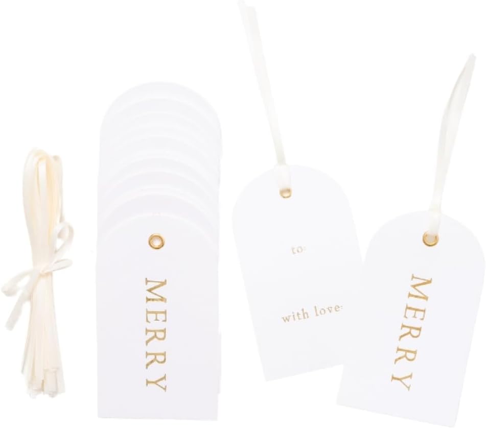 A stack of white gift tags with gold text, some reading "MERRY," alongside cream ribbon ties—perfect for pairing with your favorite glass ornaments.