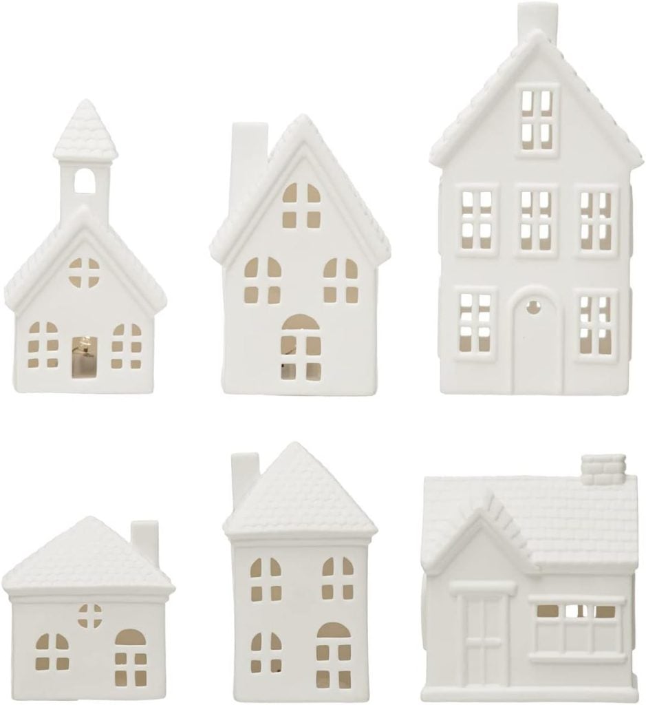 Five small, white ceramic house figurines with various roof and window styles are arranged in two rows against a plain background.