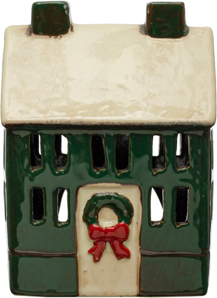 Ceramic model of a green house with a cream-colored roof, windows, and a front door decorated with a wreath and red bow.