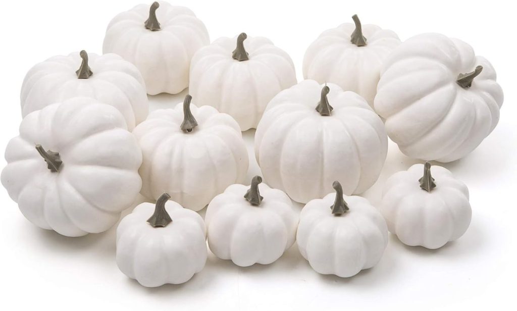 A group of twelve white pumpkins of varying sizes arranged on a white surface.