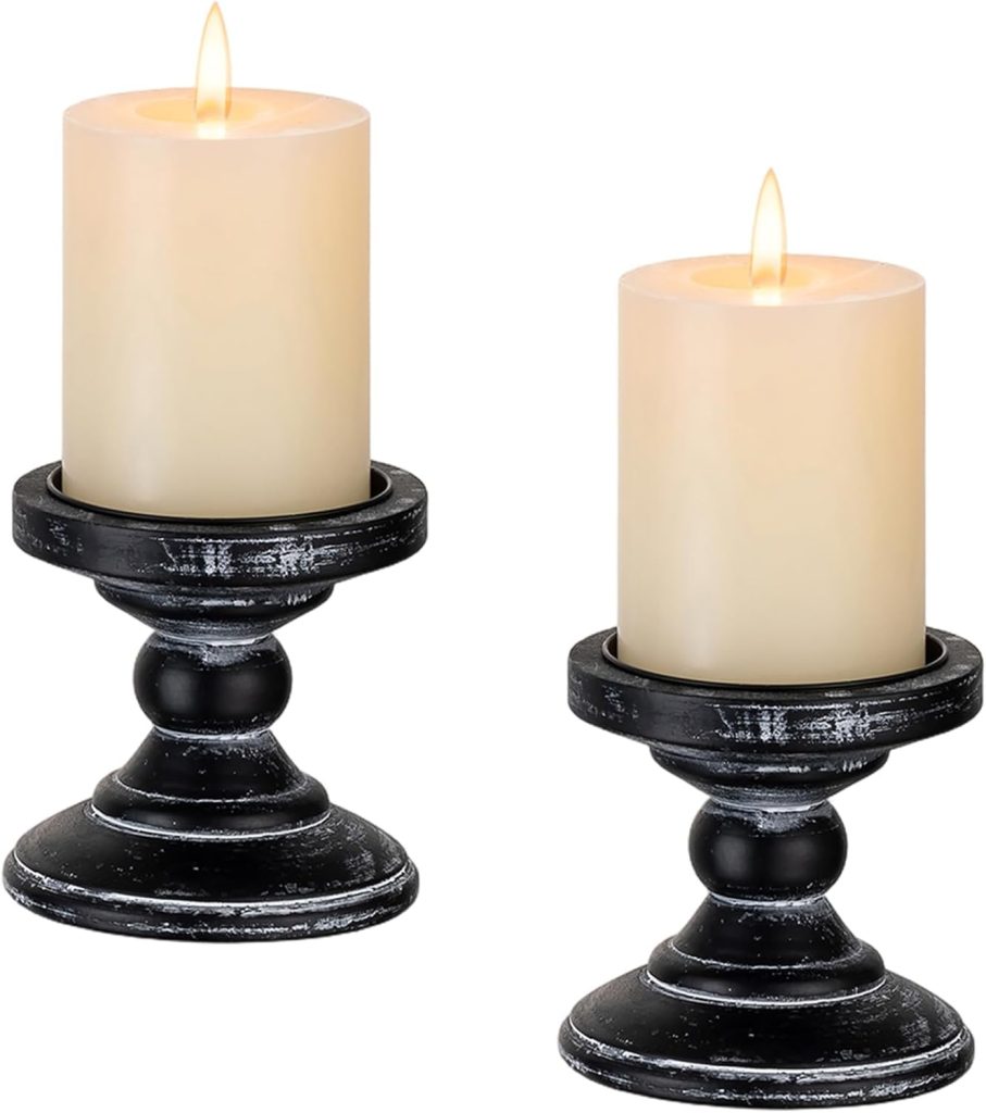 Two lit pillar candles placed on black, distressed-finish candle holders alongside charming Burlap Christmas Trees, set against a white background.