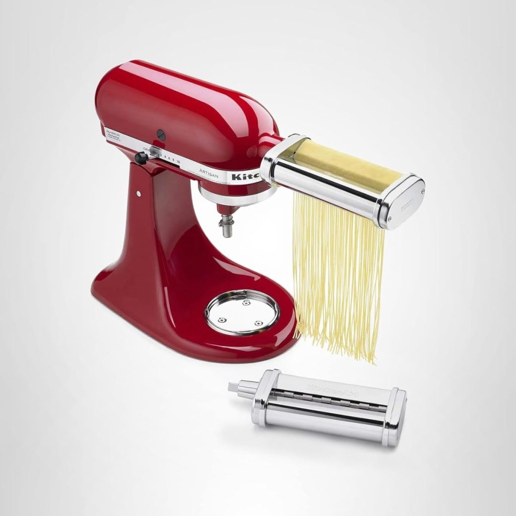 A red stand mixer with a pasta-making attachment extruding fresh pasta, plus an extra metal attachment in front, is showcased on a plain white background—perfect for upgrading your kitchen during Amazon Prime Big Deal Days.