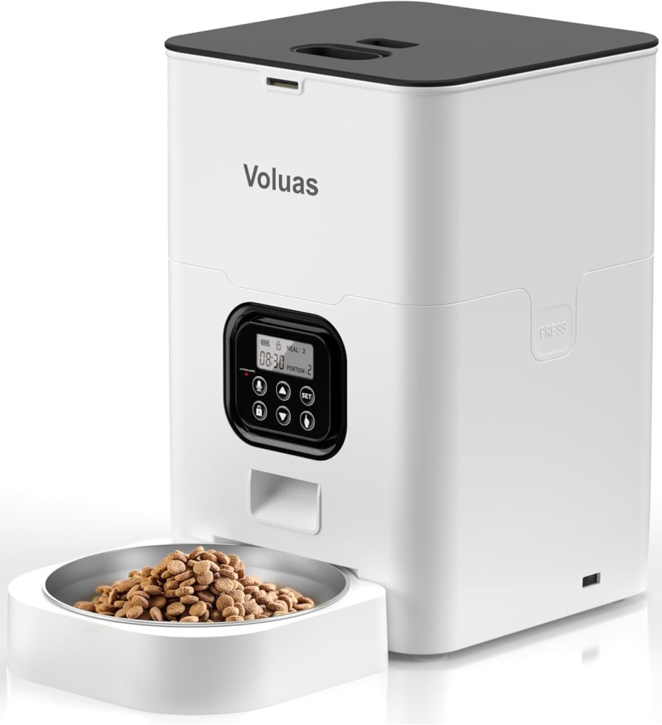 A white automatic pet feeder with digital controls dispenses dry pet food into a detachable bowl. The brand name "Voluas" is printed on the front—perfect for scoring during Amazon Prime Big Deal Days.