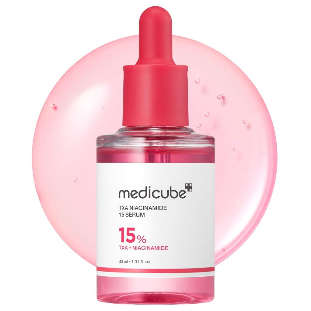 A clear bottle of Medicube TXA Niacinamide 15 Serum with a pink dropper cap, labeled “15% TXA + Niacinamide,” sits before a pink liquid background—perfect for your routine and available during Amazon Prime Big Deal Days.