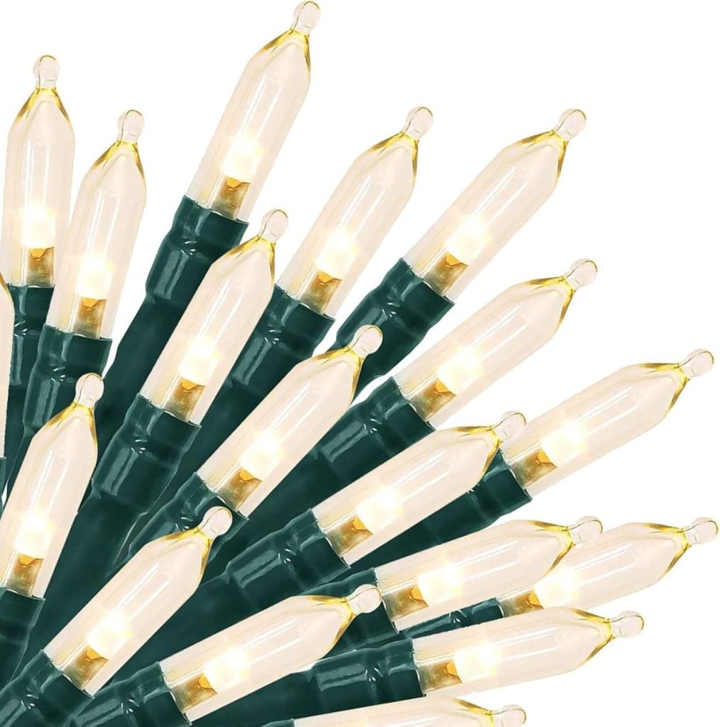 A bundle of lit white mini Christmas string lights with green wiring, arranged in a fan shape against a white background—perfect for accenting glass ornaments on your holiday display.