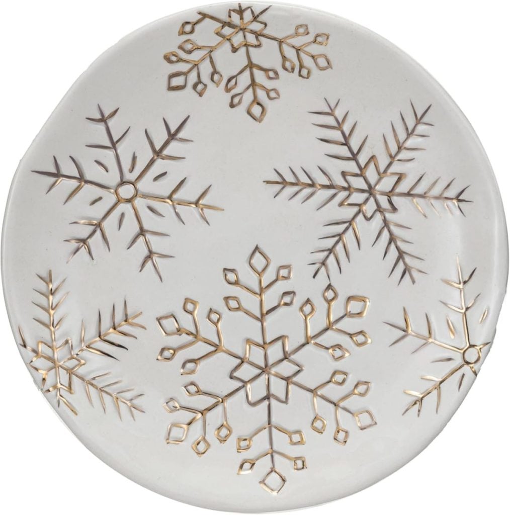 White plate with embossed gold snowflake designs arranged across the surface.