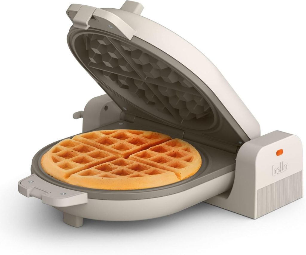 A beige waffle maker with the lid open, showing a cooked round waffle inside—perfect for breakfast lovers looking to upgrade their kitchen during Amazon Prime Big Deal Days.