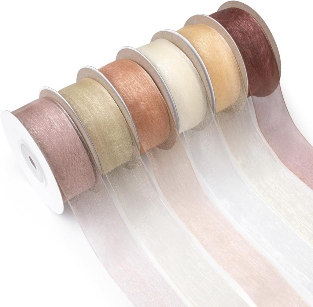 Five rolls of sheer organza ribbon in various neutral and pastel colors, unspooled and laid out in a row—perfect for wrapping gifts or accenting glass ornaments with a delicate, airy touch.
