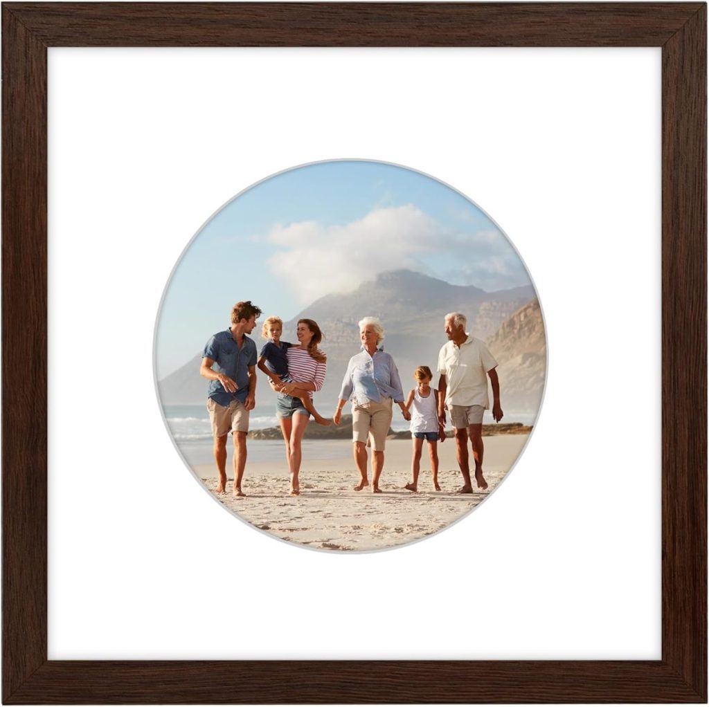 Six people of varying ages walk together on a sandy beach with mountains in the background, framed by a dark wood frame and white mat—a perfect scene to capture memories or shop for similar art during Amazon Prime Big Deal Days.