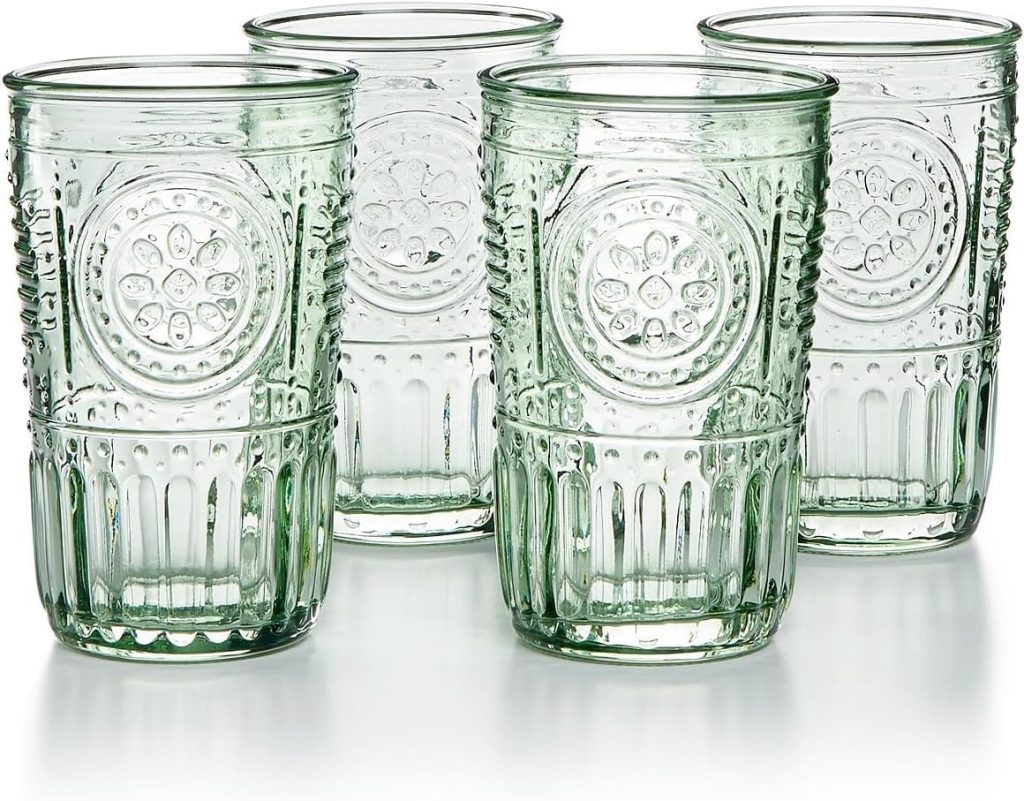 Four clear green glass tumblers with embossed circular floral patterns and vertical ribbed designs, arranged on a reflective surface.