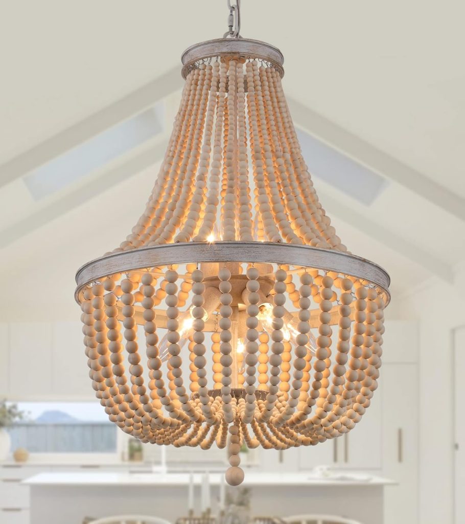 A wooden bead chandelier with multiple strands and a metallic frame hangs in a bright, modern kitchen with white cabinetry, evoking the stylish charm often found in popular Airbnb Waco homes.