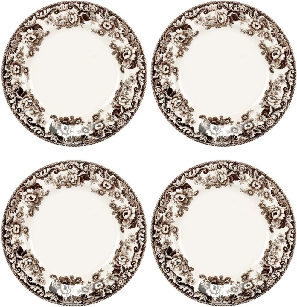 Four ornate, round plates with a floral brown pattern around the rim, arranged in a 2x2 grid on a white background.