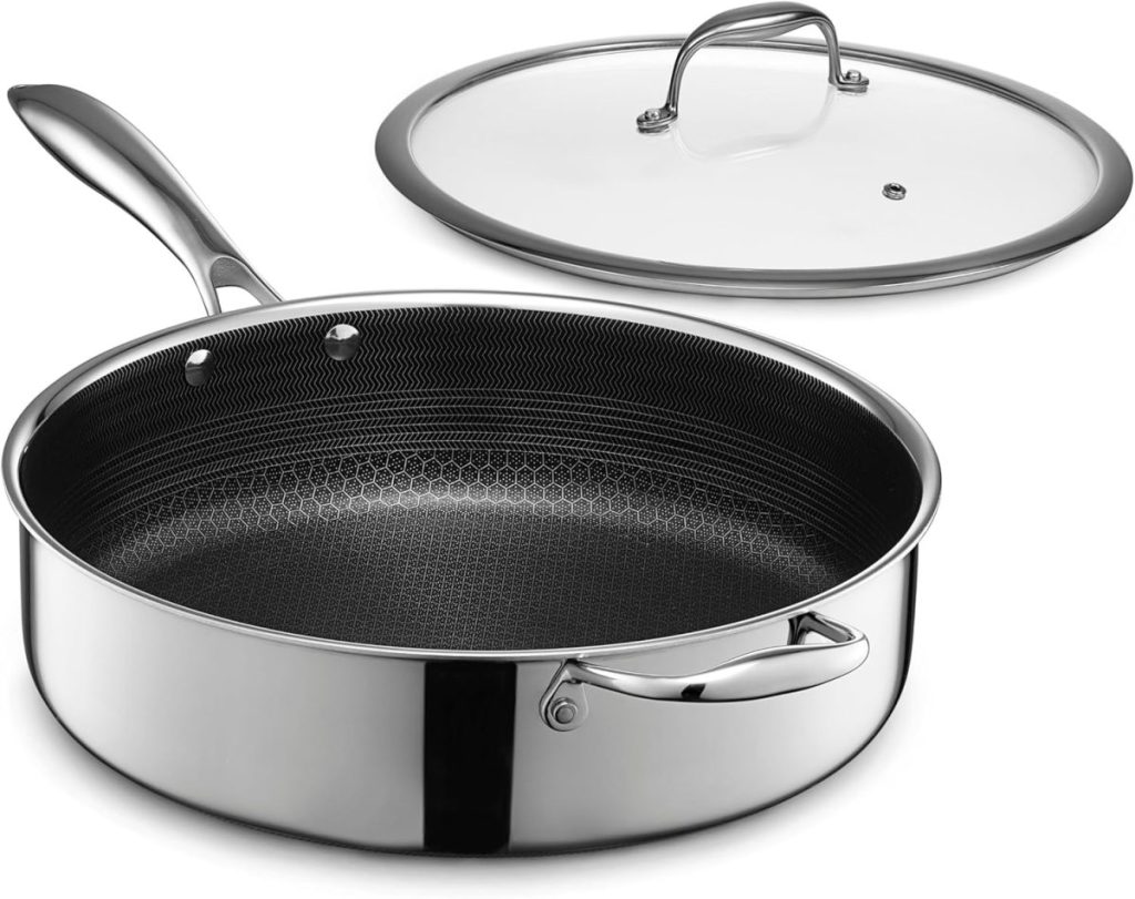 A stainless steel frying pan with a hexagonal nonstick interior pattern, featuring a metal handle and a glass lid placed beside it—perfect for preparing Marry Me Chicken.