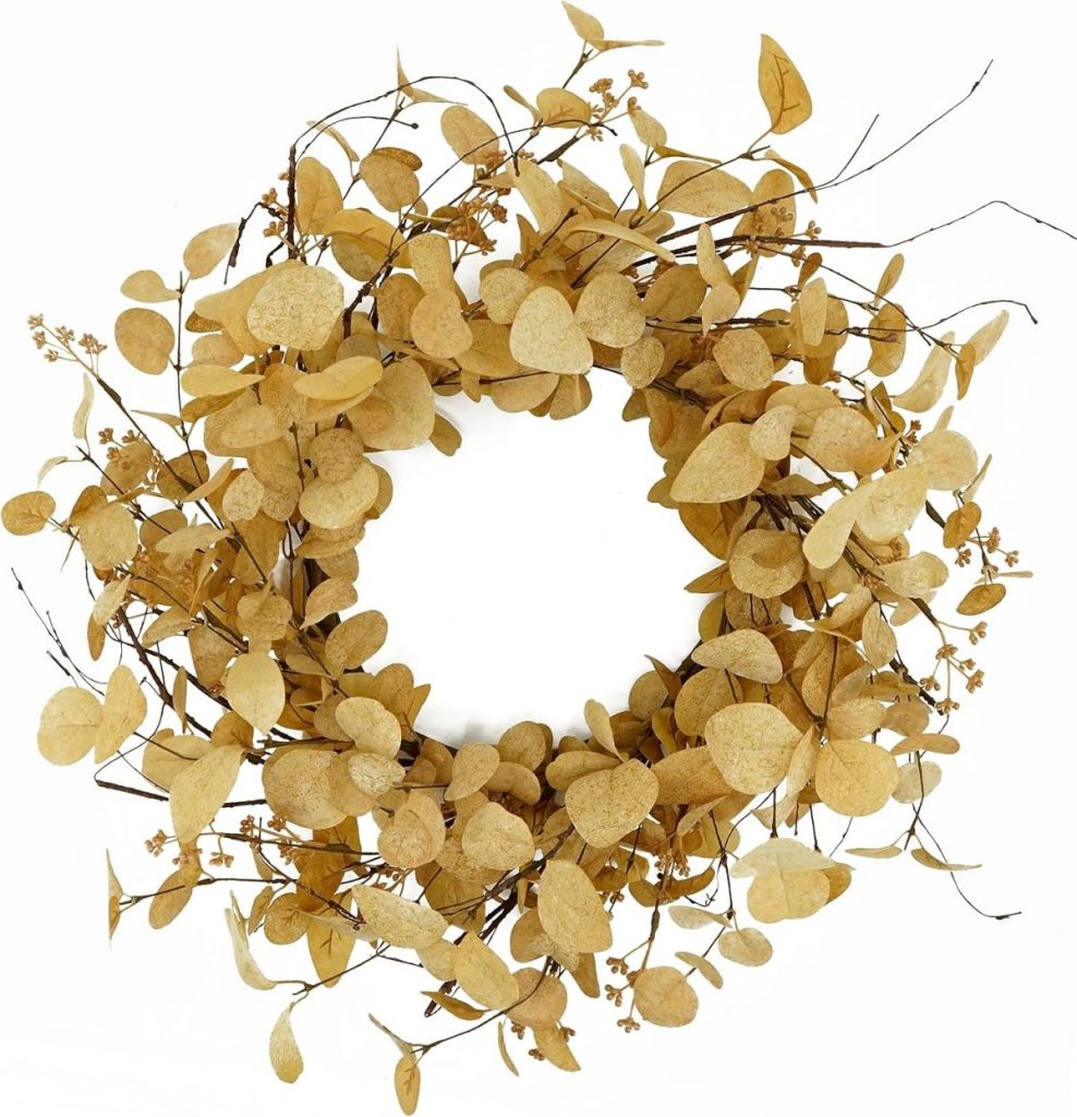 A circular wreath made of dried brown leaves and small twigs, arranged in a natural, rustic style against a white background.