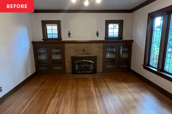 Empty living room with hardwood floors, a central brick fireplace, built-in shelves with glass doors, two windows, and dark wood trim. "Before" label in the top left corner.