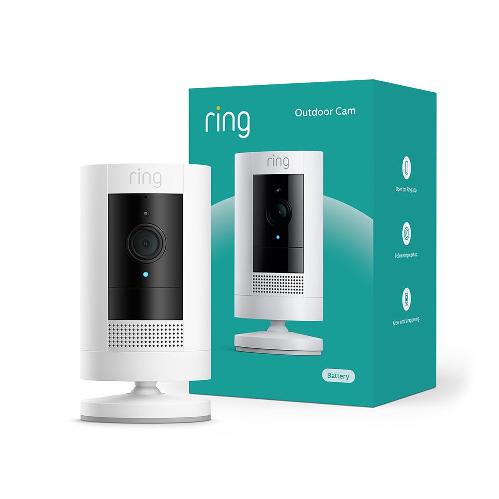 A Ring outdoor security camera is shown in front of its teal and white packaging box, alongside a festive Christmas pillow, highlighting both security and holiday spirit in your home.