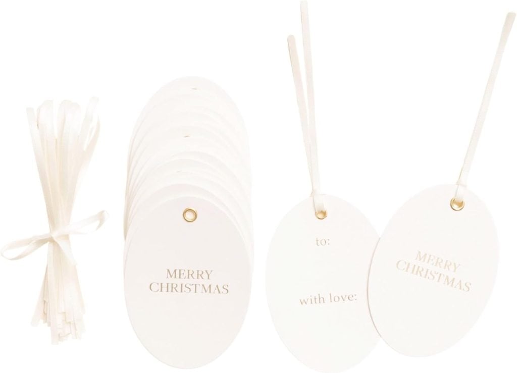 A set of white oval gift tags with "Merry Christmas" and "to: with love:" text, gold eyelets, and white ribbons for attaching.