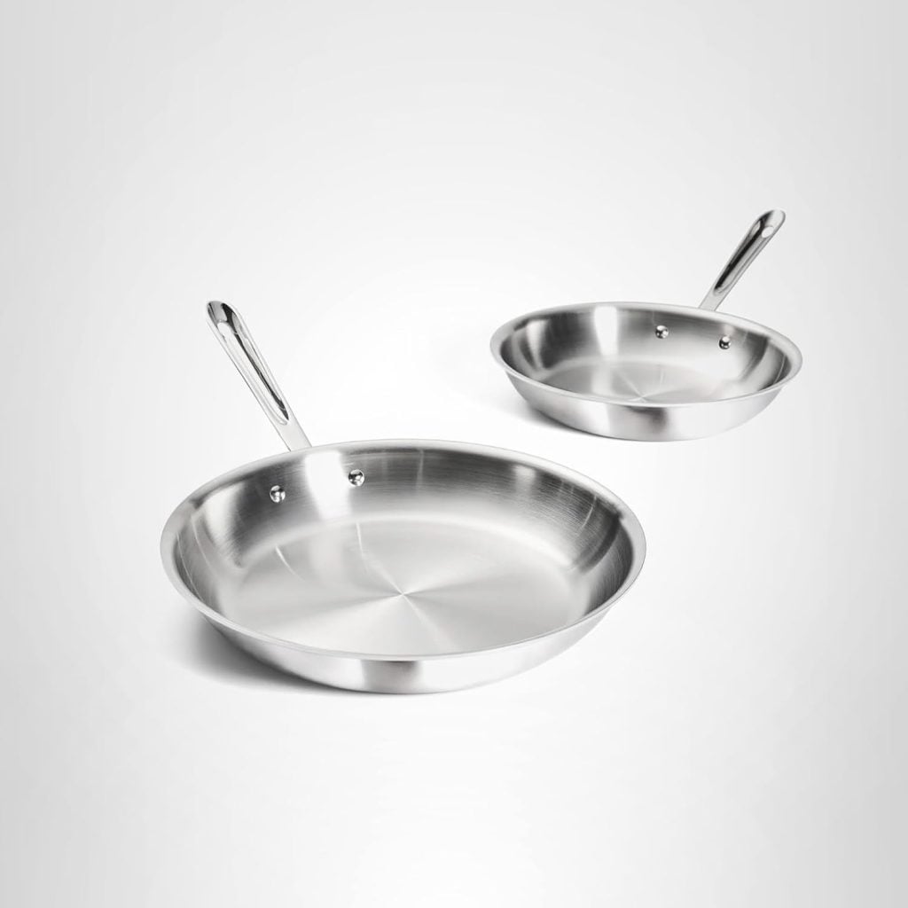 Two stainless steel frying pans of different sizes with metal handles are displayed on a plain, light background&mdash;perfect cookware to feature in your next blog posts about kitchen essentials.