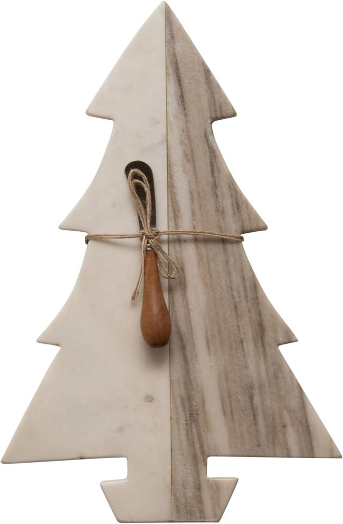 A marble cutting board shaped like a Christmas tree with a small wooden spoon tied to the center with string.