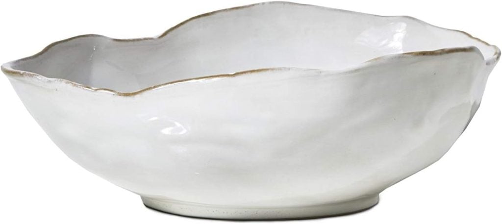 A white ceramic bowl with an irregular, wavy edge and a slightly textured surface, photographed against a plain background.