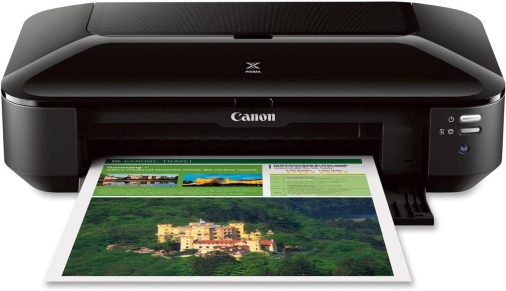 A Canon PIXMA printer outputs a color document featuring images and text, including vibrant window art designs, with the paper emerging from the front tray.